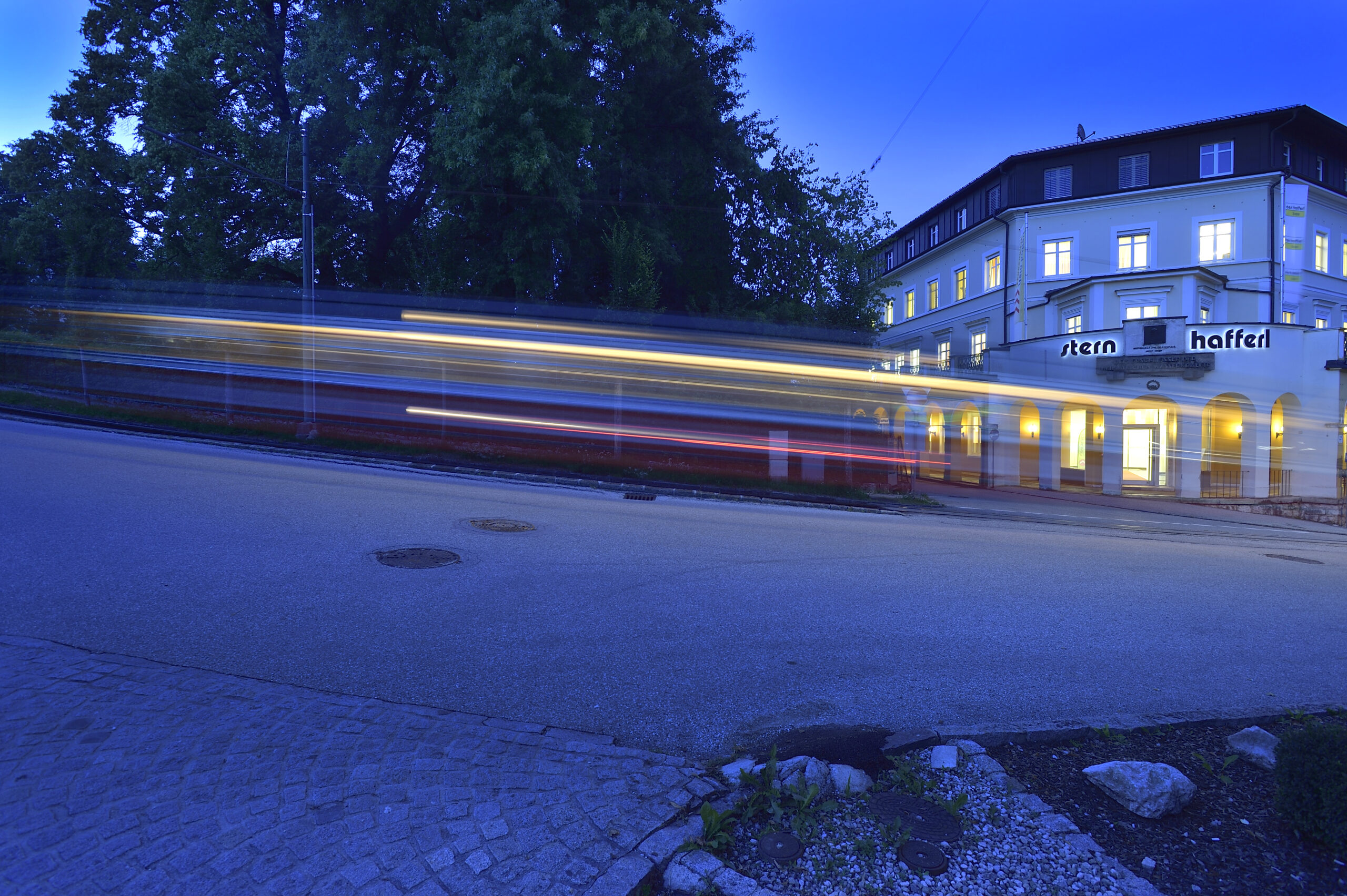 Arkadenhaus/Firmensitz von Stern & Hafferl mit einem verwischten vorbeifahrenden Zug im Vordergrund