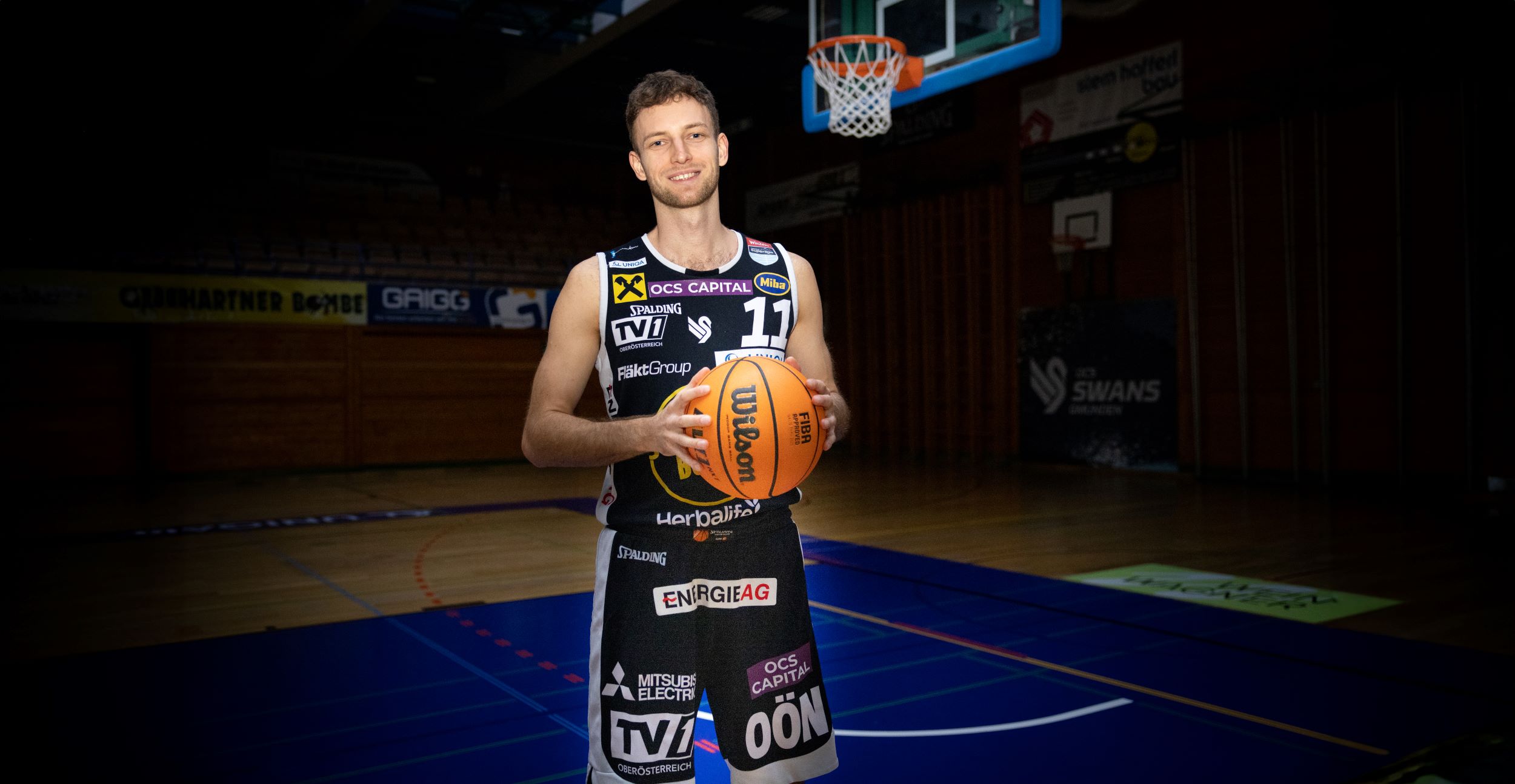 Lukas Schartmüller mit Basketball in der Hand und Basketballkorb im Hintergrund