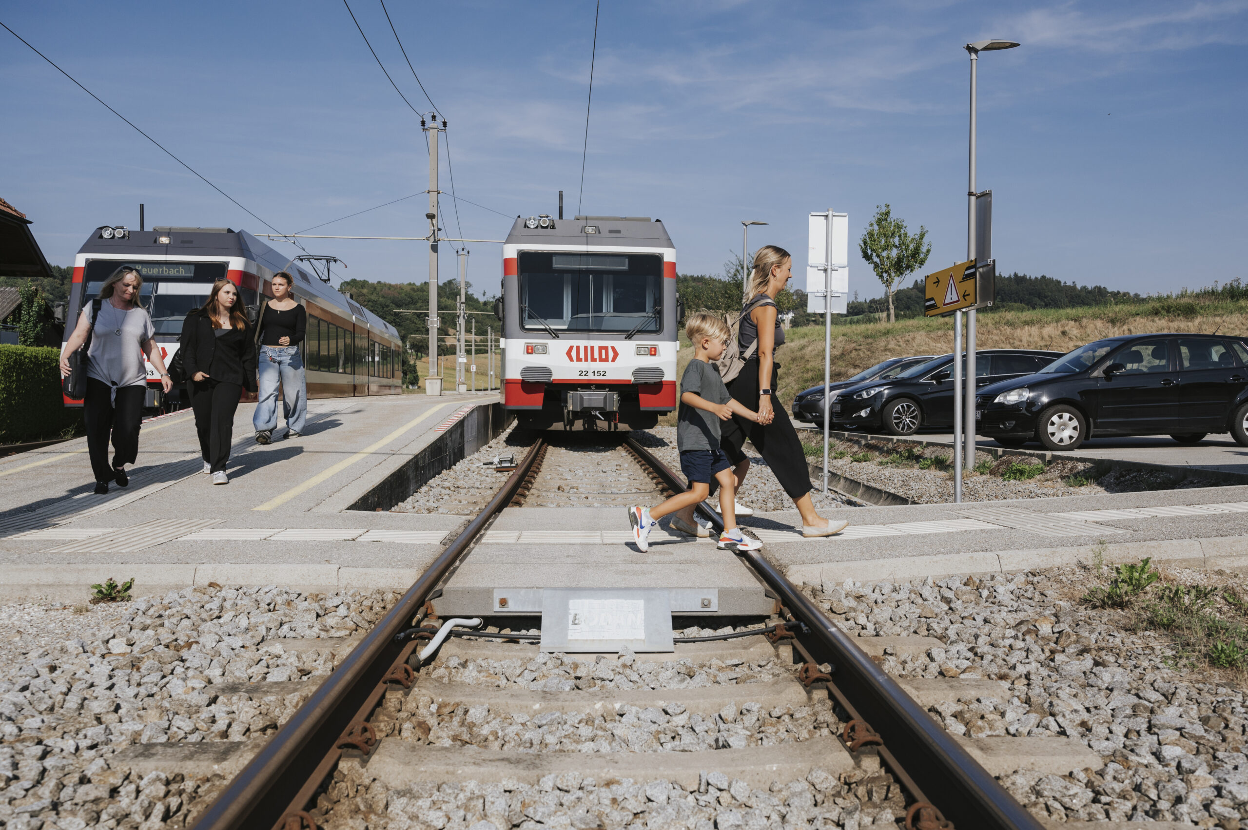 Eine Frau geht mit ihrem Kind über den Bahnübergang