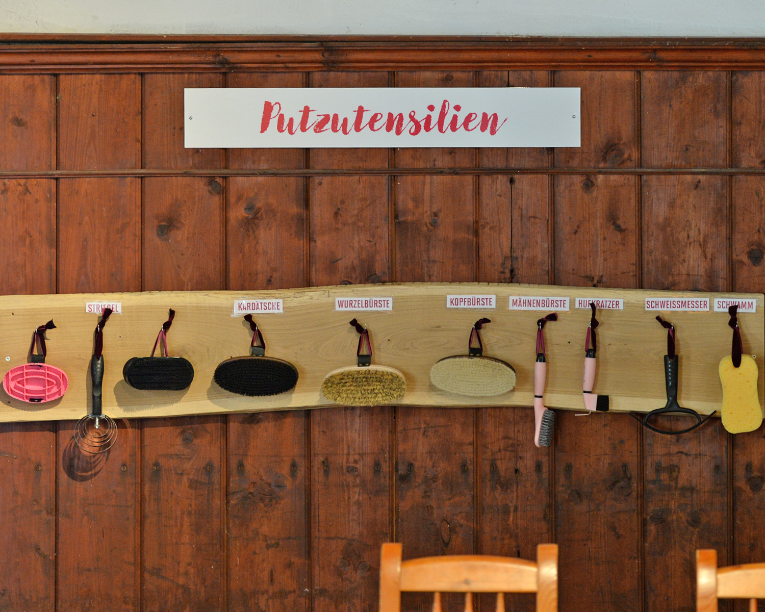 Putzutensilien hängen beschriftet and der Holzwand